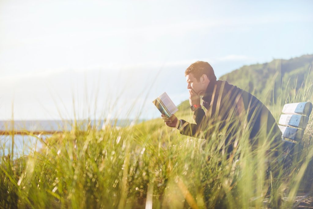 Comment améliorer sa concentration ? - plare. man reading book on beach near lake during daytime