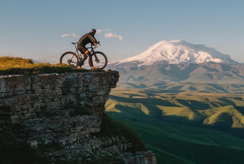 man riding bike on cliff at daytime