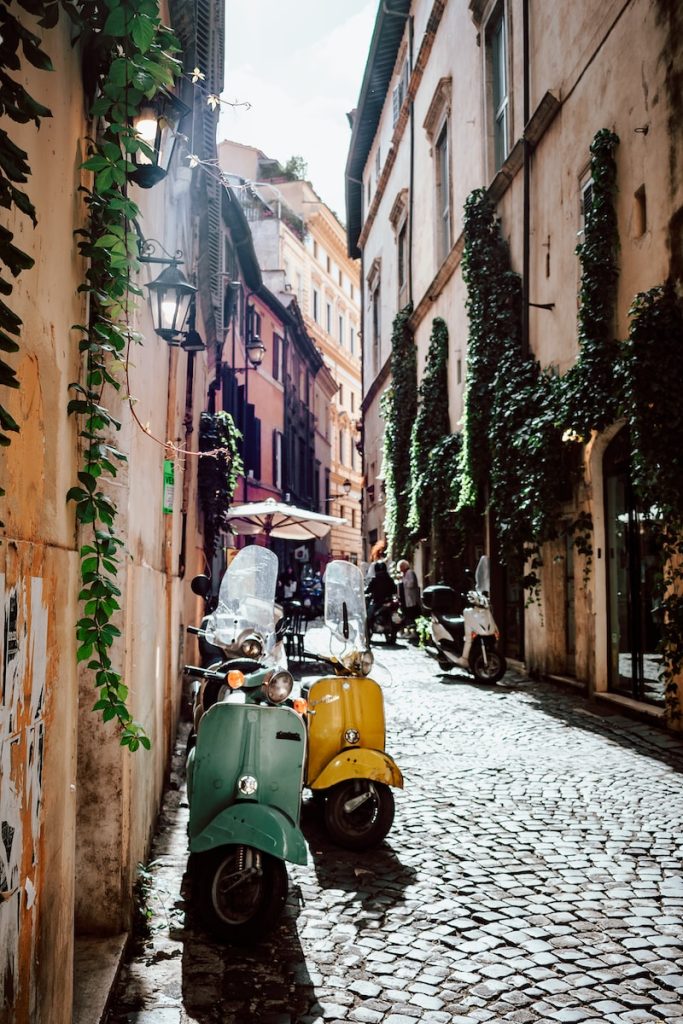 Que faire à Rome, la ville éternelle ? - plare. yellow and black motor scooter parked beside brown concrete building during daytime