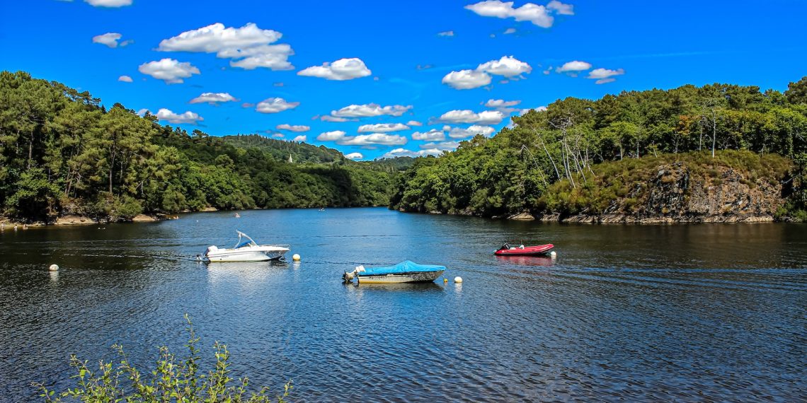 Les 7 plus beaux lacs de montagne pour se rafraîchir en été - plare. three boats floating on top of a lake surrounded by trees