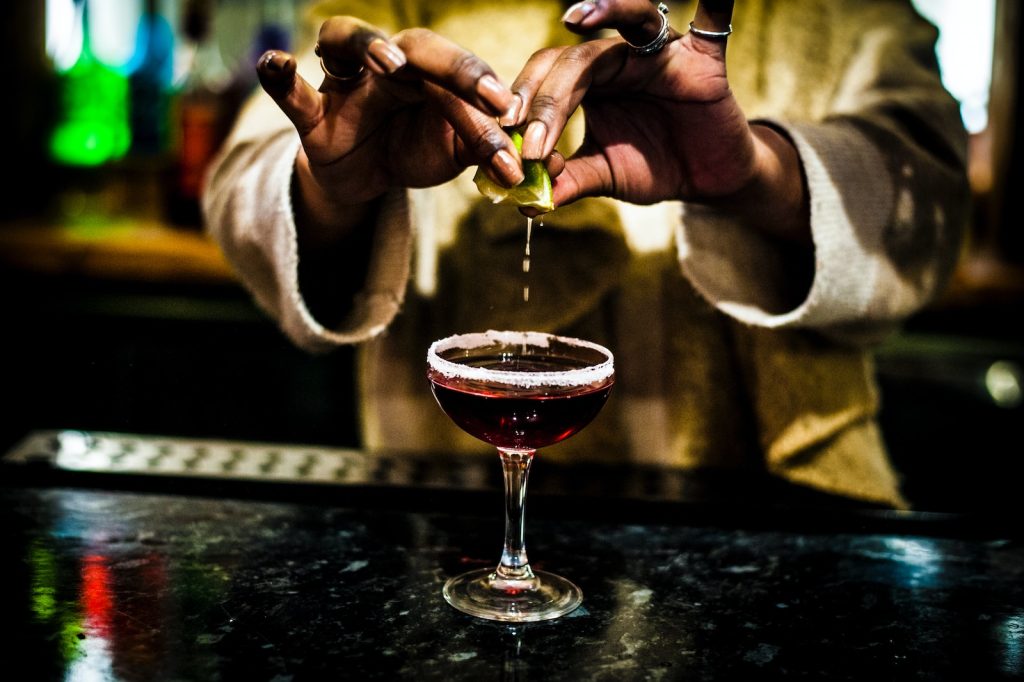 person holding clear wine glass with red wine