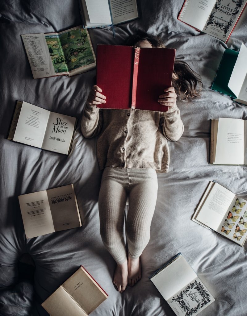 12 idées de livres pour les enfants de 2 à 3 ans - plare. a little girl laying on a bed with lots of books