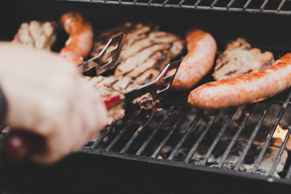 Comment bien choisir son barbecue à gaz ? - plare. person grilling sausage and meat