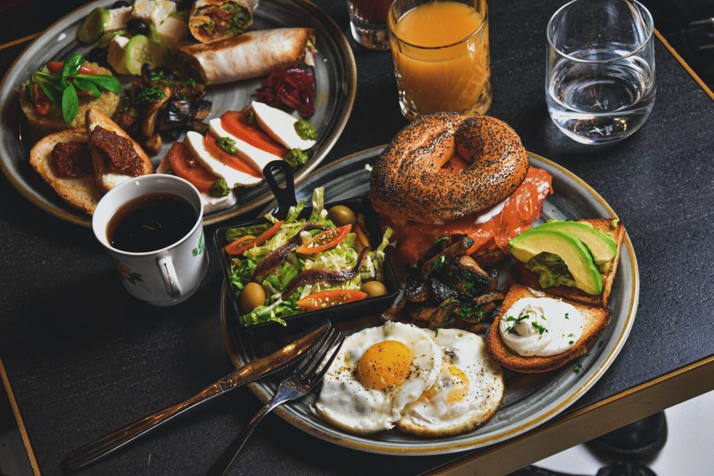 Le guide du brunch entre amis : nos idées pour le réussir - plare. hamburger, fried eggs, avocado slices, and bread on round gray plate